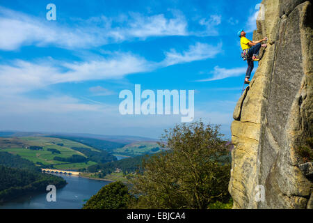 Kletterer in Gelb auf Bamford Kante, Derbyshire, Peak District, mit Ladybower Reservoir hinter Stockfoto