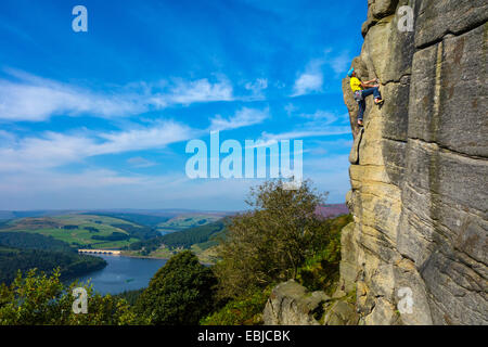 Kletterer in Gelb auf Bamford Kante, Derbyshire, Peak District, mit Ladybower Reservoir hinter Stockfoto