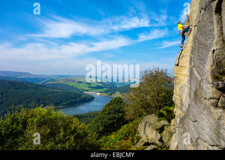 Kletterer in Gelb auf Bamford Kante, Derbyshire, Peak District, mit Ladybower Reservoir hinter Stockfoto