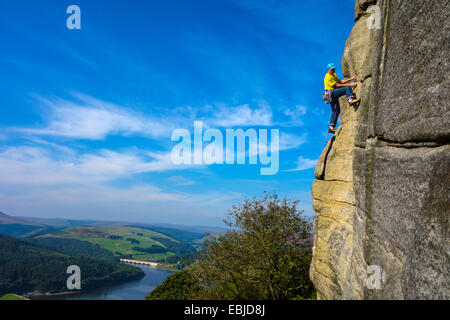 Kletterer in Gelb auf Bamford Kante, Derbyshire, Peak District, mit Ladybower Reservoir hinter Stockfoto