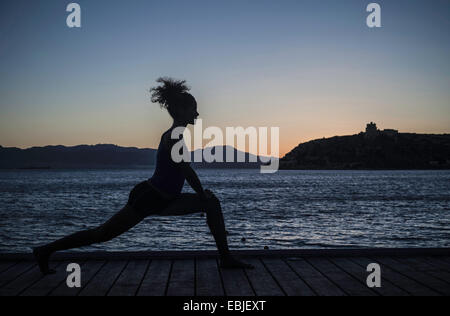 Junge Frau beim Yoga auf dem Seeweg, Silhouette Stockfoto