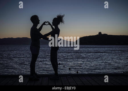 Paar, machen, Herz-Form mit Händen auf dem Seeweg, silhouette Stockfoto