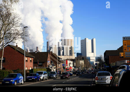 Blick durch Stadtstraße mit drohenden und Rauchen Braunkohle-Kraftwerk Niederaußem, Deutschland, Nordrhein-Westfalen, Niederaußem, Bergheim Stockfoto