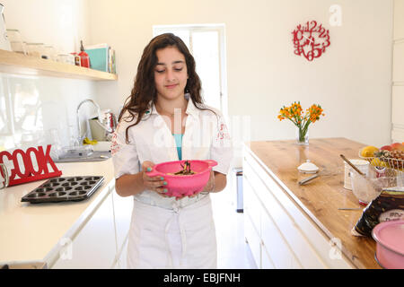 Teenager-Mädchen in weißer Schürze backen Kuchen in Küche Stockfoto