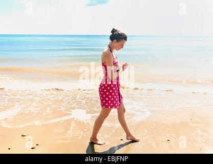 Junge Frau, die zu Fuß am Strand Stockfoto