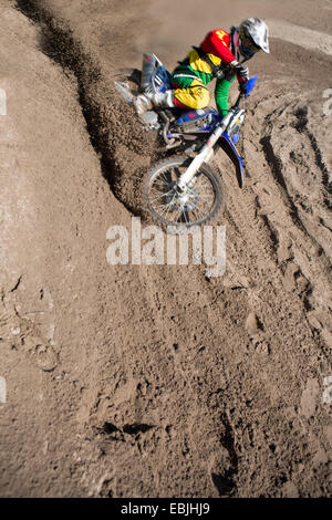 Junge männliche Motocross-Fahrer Rennen bergab Schlamm Stockfoto