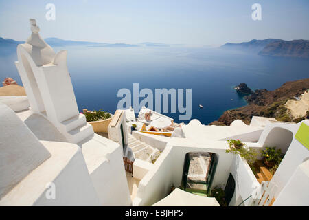 Blick von der Kirche über das Dorf entlang der steilen Küste in die spektakuläre Caldera gebildet von der Insel, Oia, Santorin, Griechenland, Cyclades Stockfoto