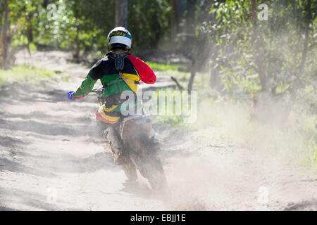 Rückansicht des jungen männlichen Motocross-Fahrer racing auf Waldweg Stockfoto