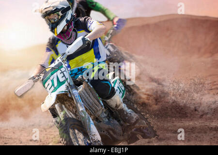 Zwei junge männliche Motocross-Fahrer racing auf schlammigen Strecke Stockfoto