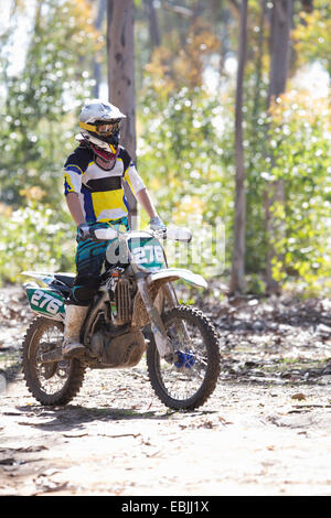 Junge männliche Motocross Racer stehen während der Fahrt durch Wald Stockfoto