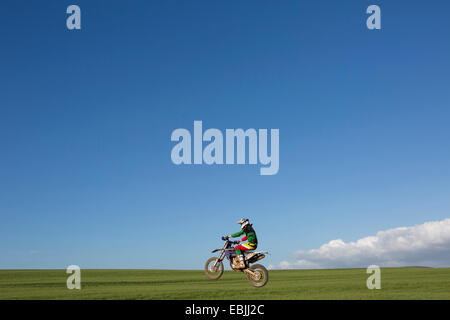 Junge männliche Motocross Racer über Feld reiten Stockfoto