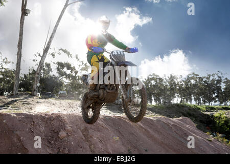 Junge männliche Motocross Racer Luft Schlamm Hügel hinunter springen Stockfoto