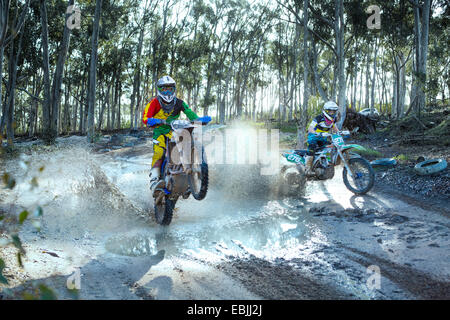 Zwei junge männliche Motocross-Fahrer, die auf staubigen Track racing Stockfoto