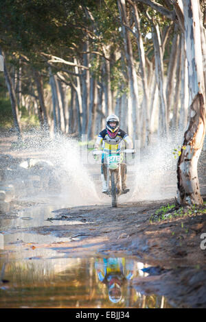 Junge männliche Motocross Racer durch Pfütze im Wald Stockfoto