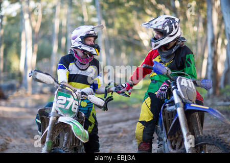 Zwei junge männliche Motocross-Fahrer im Chat auf Wald verfolgen Stockfoto