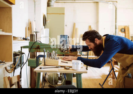 Mitte adult Handwerker mit Maschine in Orgel-Werkstatt Stockfoto