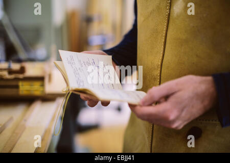 Nahaufnahme von Mitte adult Handwerker mit Notebook in Orgelwerkstatt Stockfoto