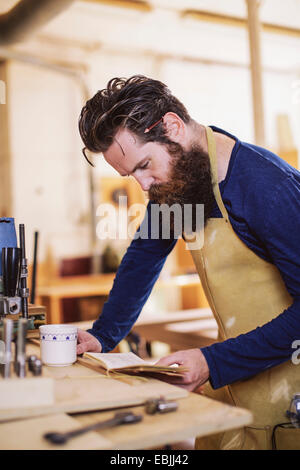 Mitte adult Handwerker Notizbuch in der Orgelwerkstatt überprüfen Stockfoto