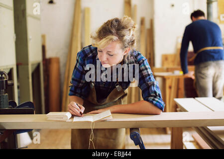 Junge Handwerkerin Notizen in Orgel-Werkstatt Stockfoto