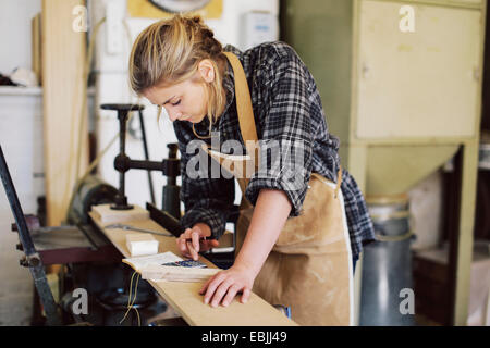 Junge Handwerkerin mit Taschenrechner in Orgel-Werkstatt Stockfoto