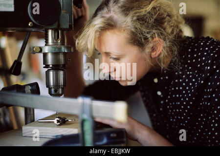 Junge Handwerkerin Bohren Komponente in Orgel-Werkstatt Stockfoto