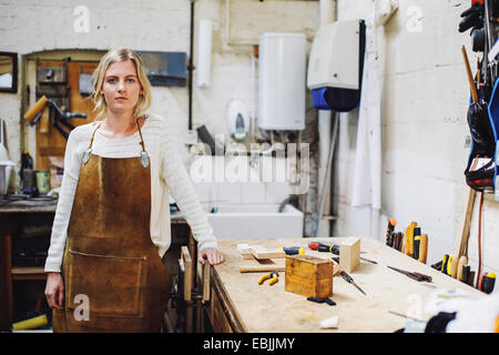 Porträt des jungen Handwerkerin stützte sich auf die Werkbank in Orgelwerkstatt Stockfoto