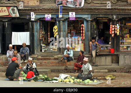 Menschen sitzen vor den Geschäften in einer Straße von der kleinen Stadt in der Nähe von Katmandoo, Nepal, Patan Stockfoto