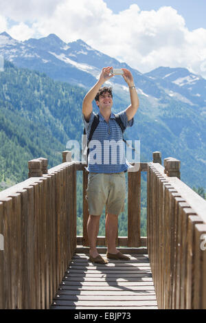 Junger Mann unter Smartphone Selfie vor Bergen, Formazza, Verbania, Piemont, Italien Stockfoto