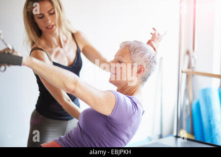 Weibliche Schüler und Lehrer praktizieren Pilates auf Trapez-Tisch in Pilates-Fitness-Studio Stockfoto