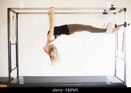 Reife Frau praktizieren Pilates auf Trapez-Tisch in Pilates-Fitness-Studio Stockfoto