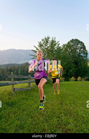 junges Paar Trailrunning in einer Wiese und Wald Landschaft, Österreich, Steiermark, Dachstein Stockfoto