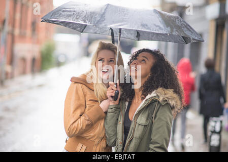 Junge Frauen, die bergende unter Dach Stockfoto