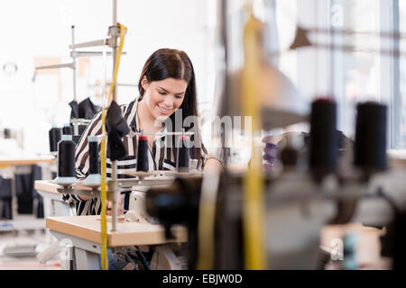 Junge weibliche Schneiderin mit Nähmaschine in Werkstatt Stockfoto