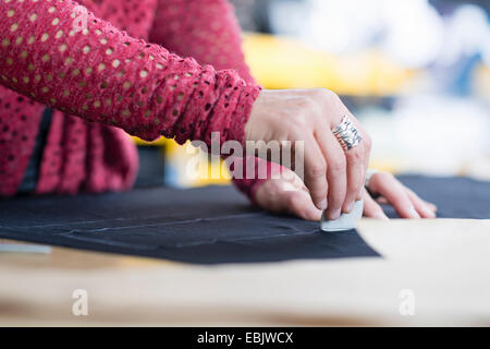 Händen der Reife Näherin Kreidung Umriss auf Textil auf Arbeitstisch Stockfoto