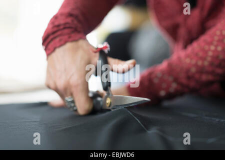 Nahaufnahme von Schneiderin Hände mit einer Schere schneiden Textil am Arbeitstisch Stockfoto