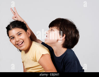 Jungen und Mädchen spielen, junge junge hält Finger als Hasenohren Stockfoto