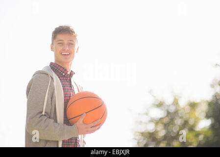 Porträt von lächelnden jungen Mann halten basketball Stockfoto