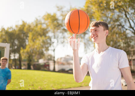 Lächelnde junge männliche Basketballspieler Ausgleich Basketball am finger Stockfoto