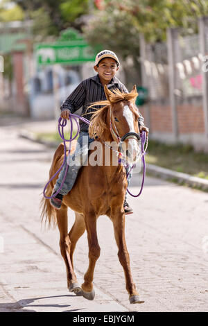 Ein junger mexikanischer Cowboy Herden Vieh hinunter eine Dorfstraße von mexikanischen Cowboys 5. November 2014 in beherbergt, Mexiko. Stockfoto