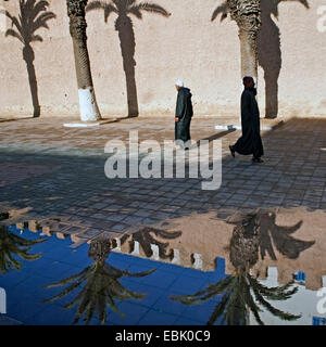 Fußgänger eine historische Stadtmauer widerspiegelt in Pfütze Wasser nach Ain Dusche, Marokko Essaouira