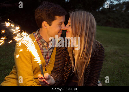 Junges Paar Nase an Nase im Park mit funkelnden Feuerwerk Stockfoto