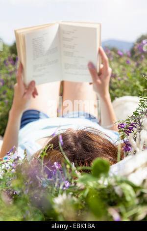 Junge Frau im Feld Lesebuch liegend Stockfoto