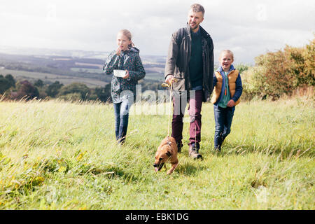 Vater und zwei Mädchen Hund im Feld Stockfoto