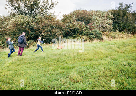 Vater und zwei Mädchen Hund im Feld Stockfoto