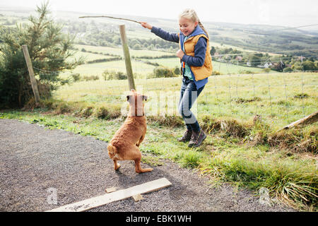 Mädchen hält Stock für Hund Stockfoto