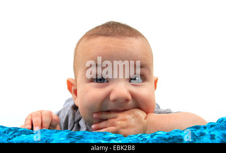 Baby in einem Bett auf dem Bauch liegend, mit einer Hand in den Mund Stockfoto
