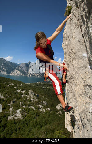 Frau Klettern in einer senkrechten Felswand über dem Abgrund, Italien, Gardasee, Arco Stockfoto