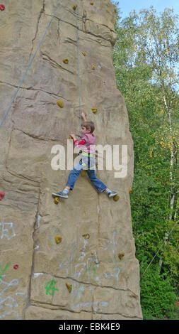 kleiner Junge Klettern angeseilt in eine professionelle Kletterwand Stockfoto