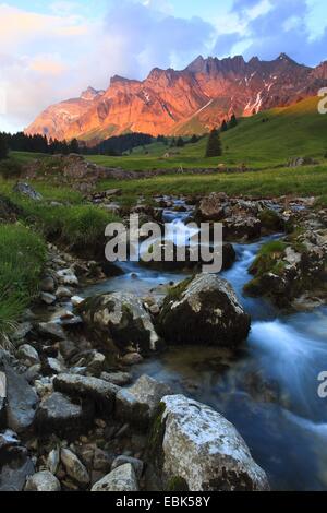 Blick von einer Bergwiese mit einem Bach im Alpstein-massiv mit dem höchsten Berg Säntis (2502 m) im Abendrot, Schweiz Stockfoto