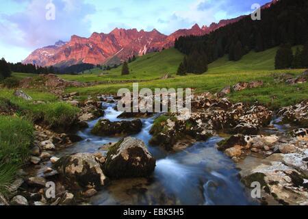 Blick von einer Bergwiese mit einem Bach im Alpstein-massiv mit dem höchsten Berg Säntis (2502 m) im Abendrot, Schweiz Stockfoto